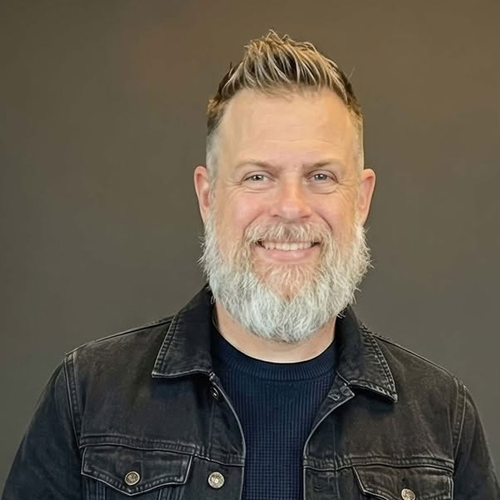 Phil Kyprianou, smiling, in a dark denim jacket